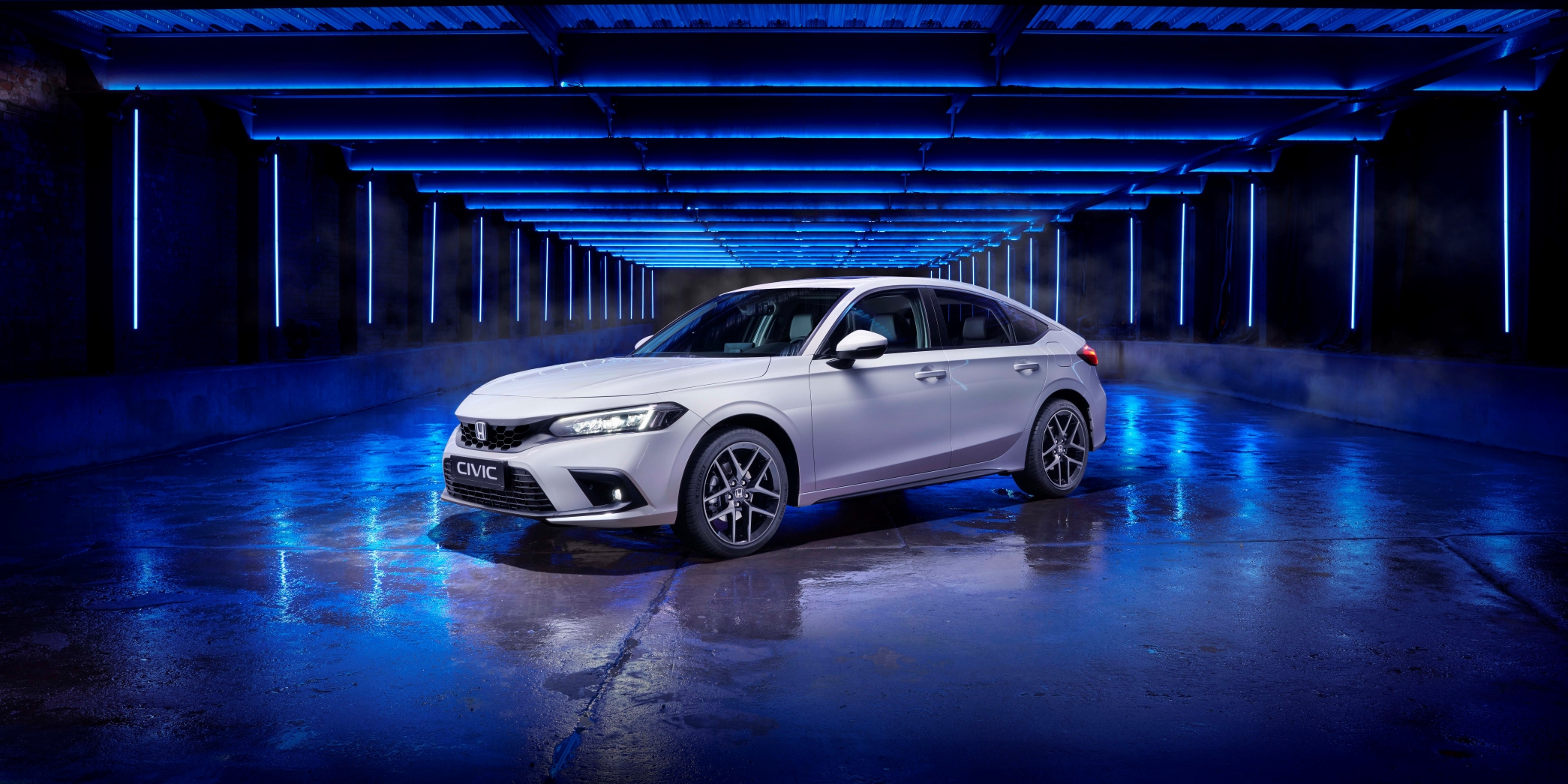 Trojštvrťový predný štúdiový záber nového bieleho modelu Honda Civic z roku 2022 s modrým nasvietením.